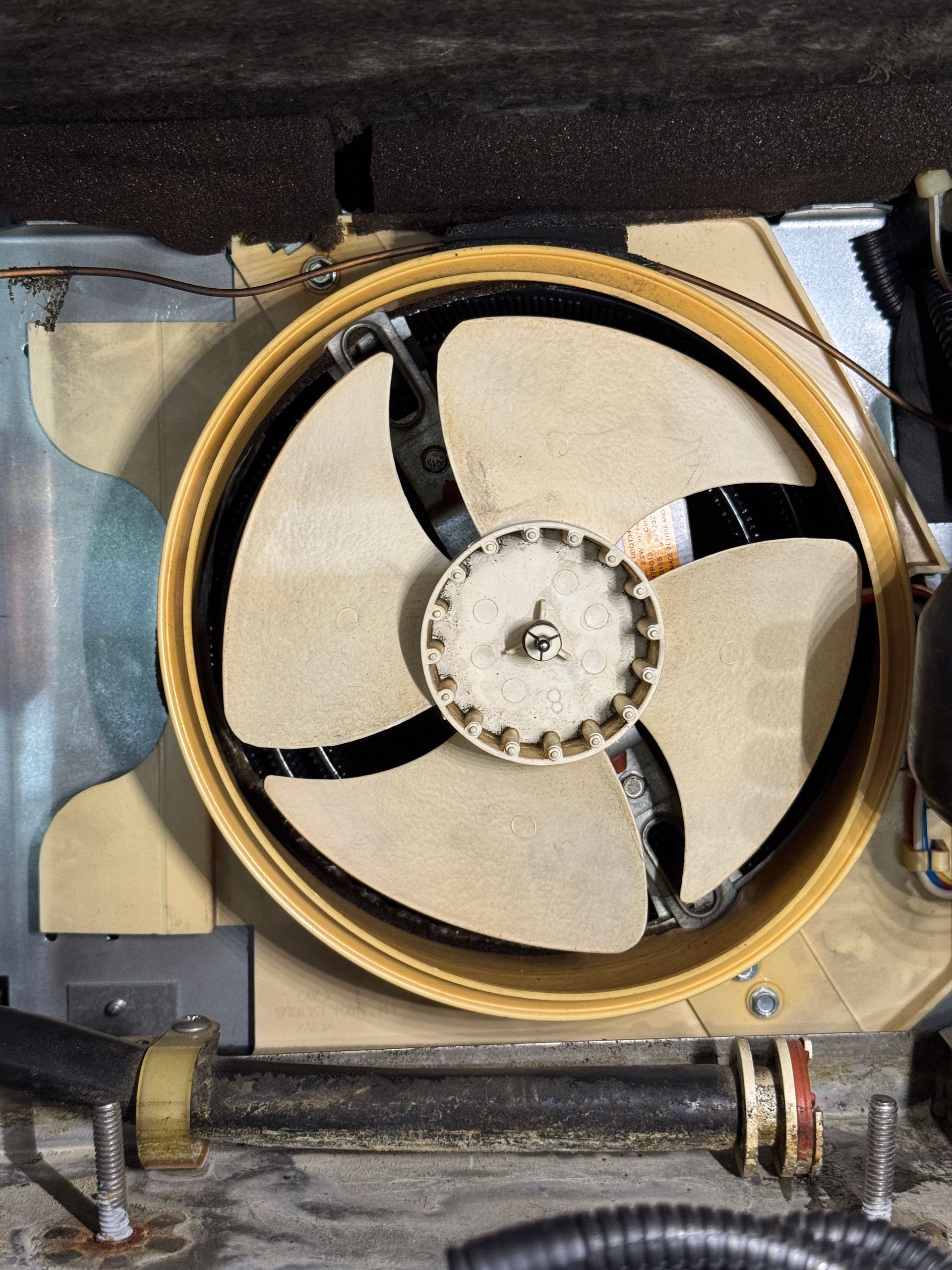 Fan with three blades inside a beige housing.