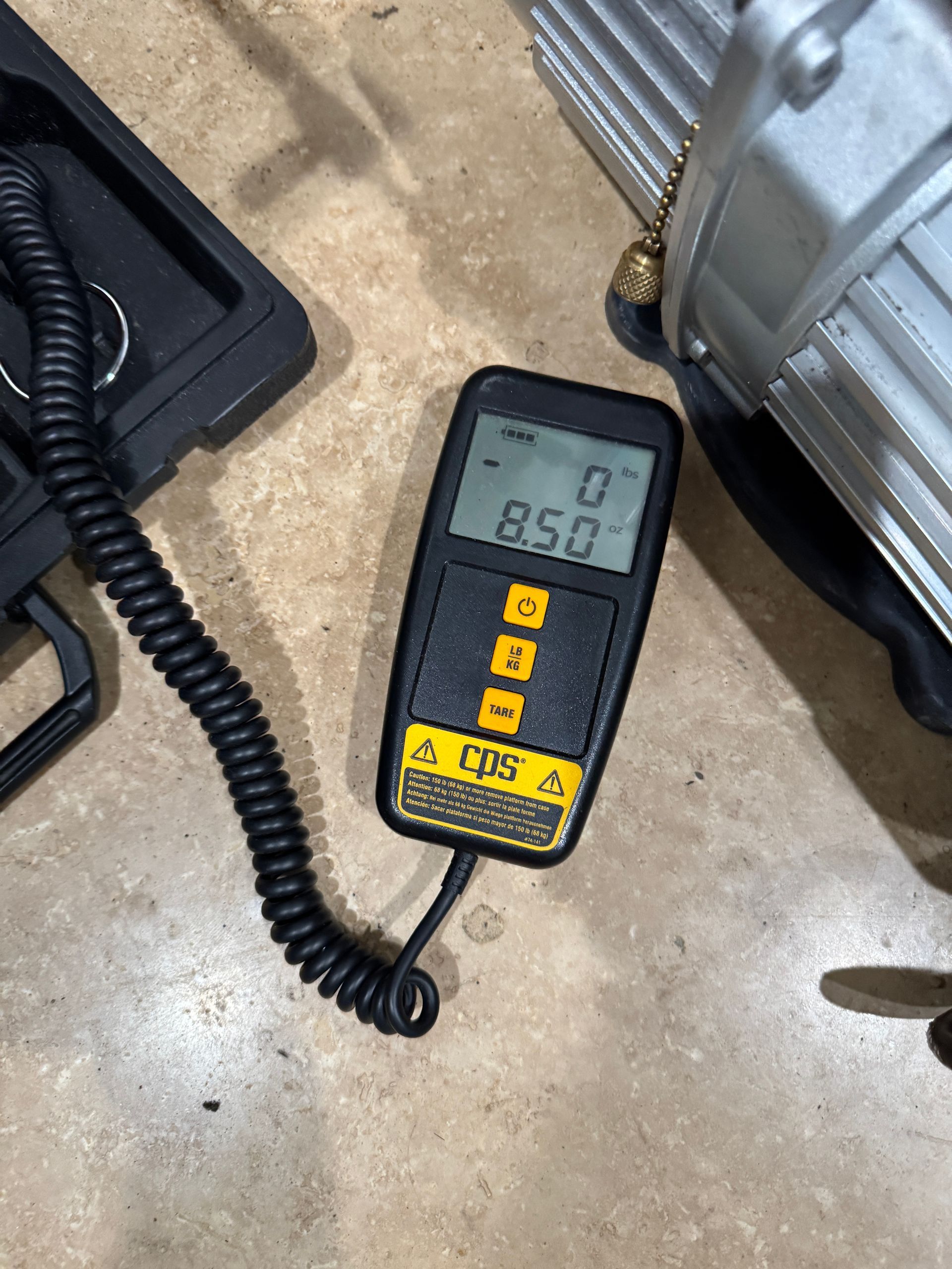 Black and yellow digital vacuum gauge displaying a reading of 850, next to a vacuum pump.