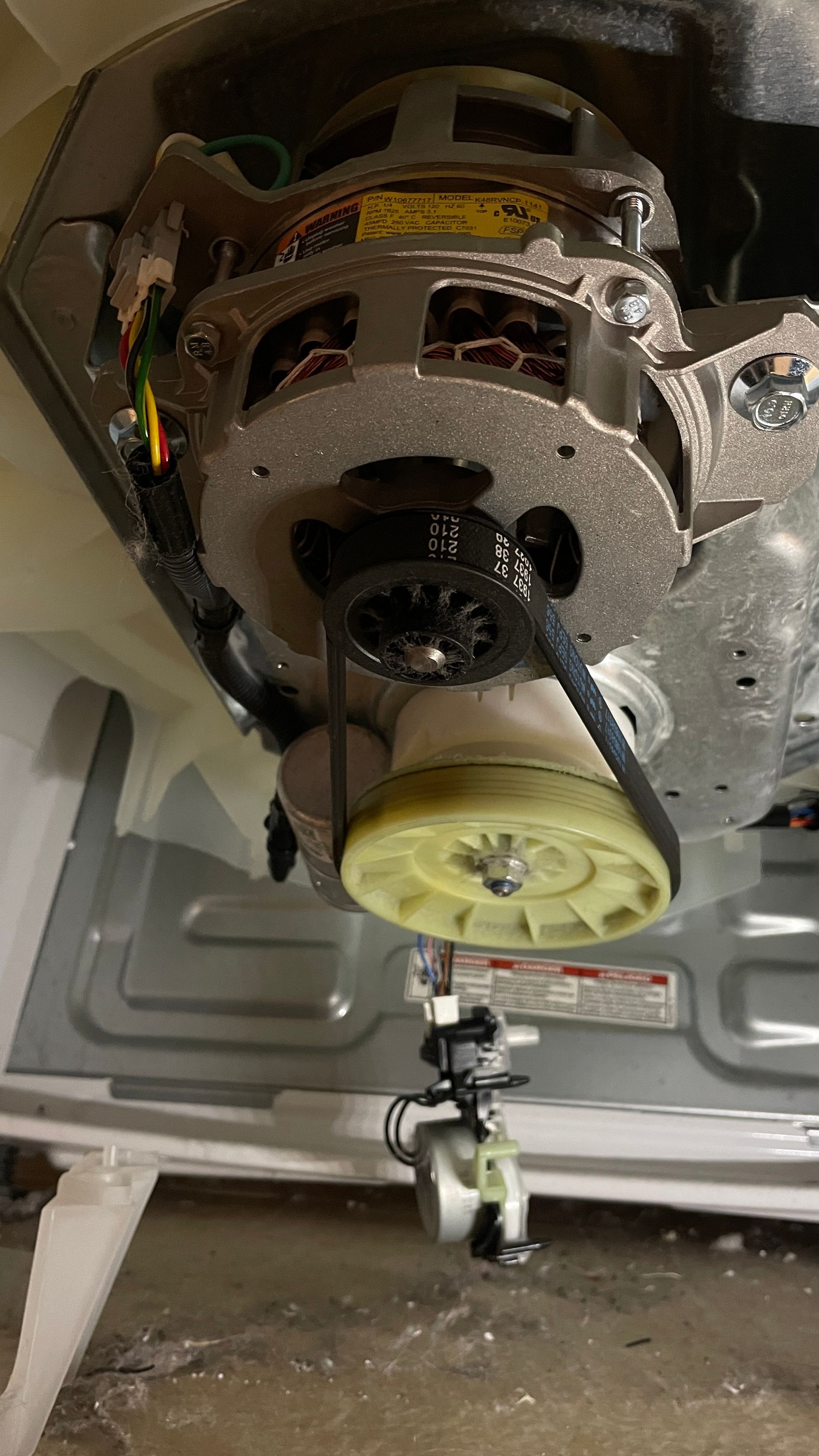 Washing machine motor assembly: A dark belt connects a grey motor to a yellow pulley.