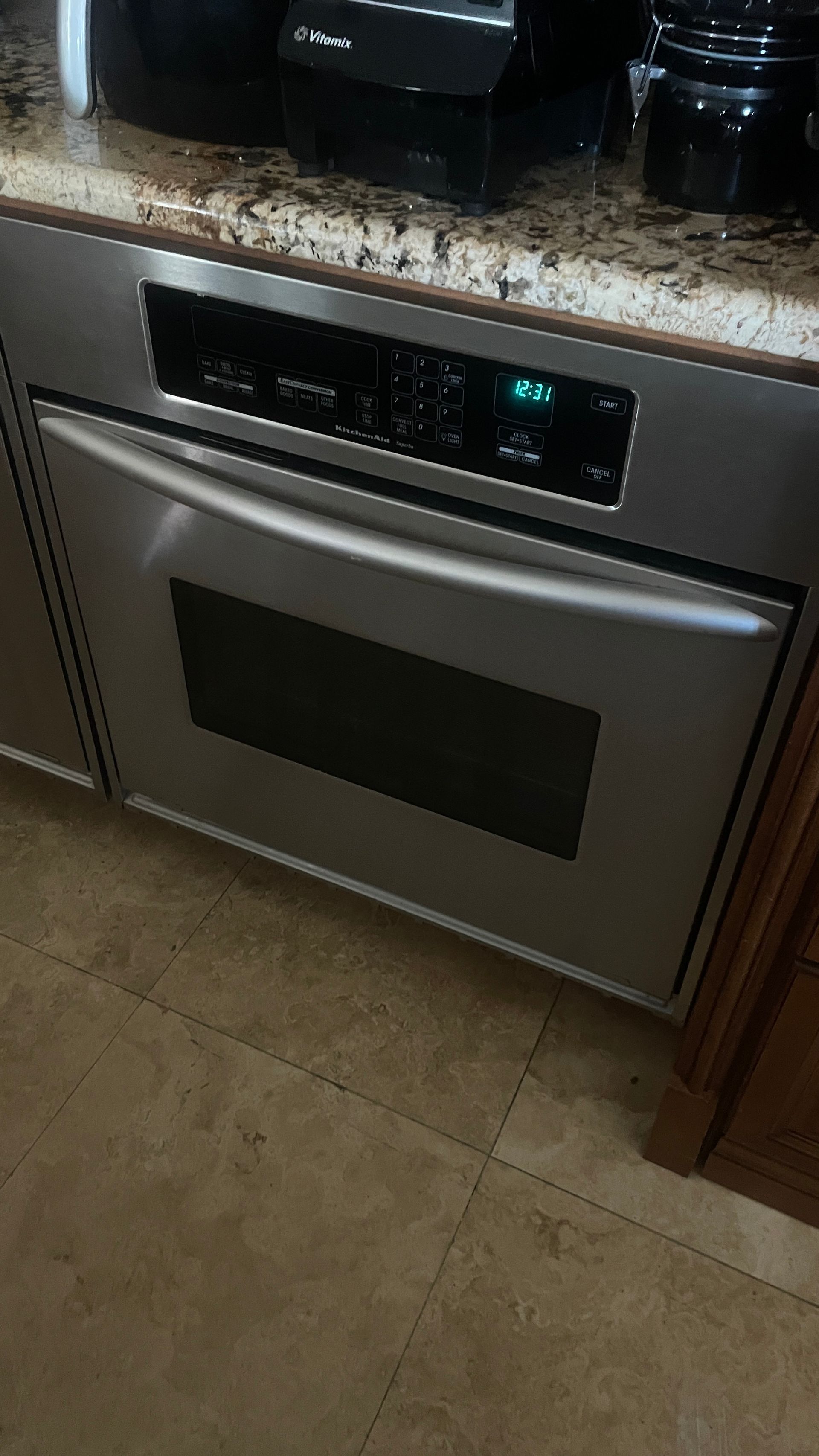 Stainless steel oven built into a kitchen cabinet, with control panel lit.