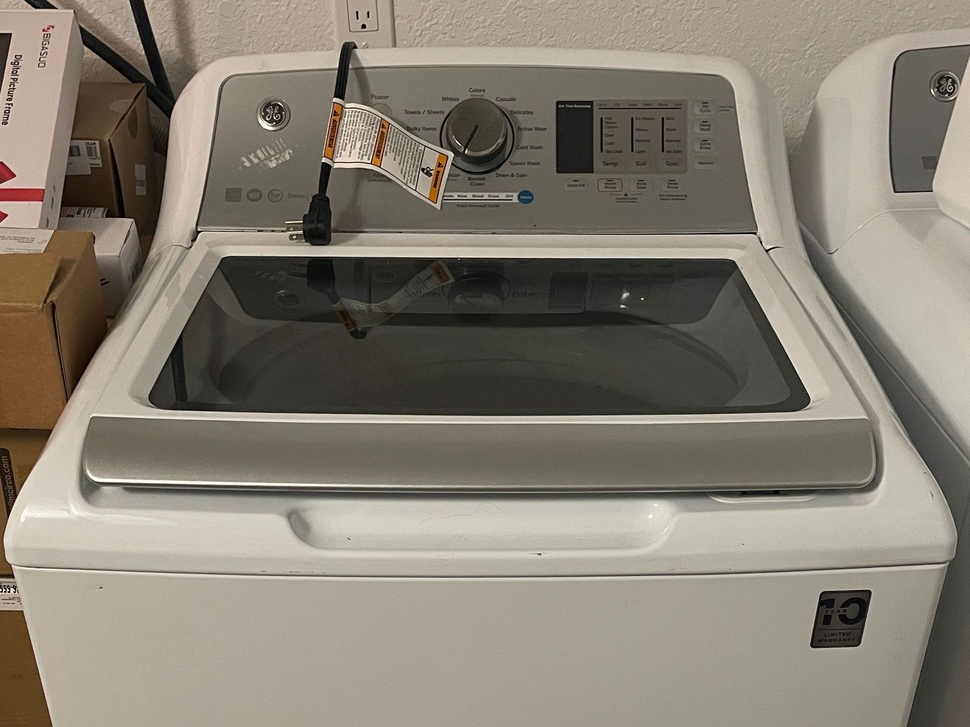White Whirlpool top-load washing machine with control panel and open lid, cord plugged in.