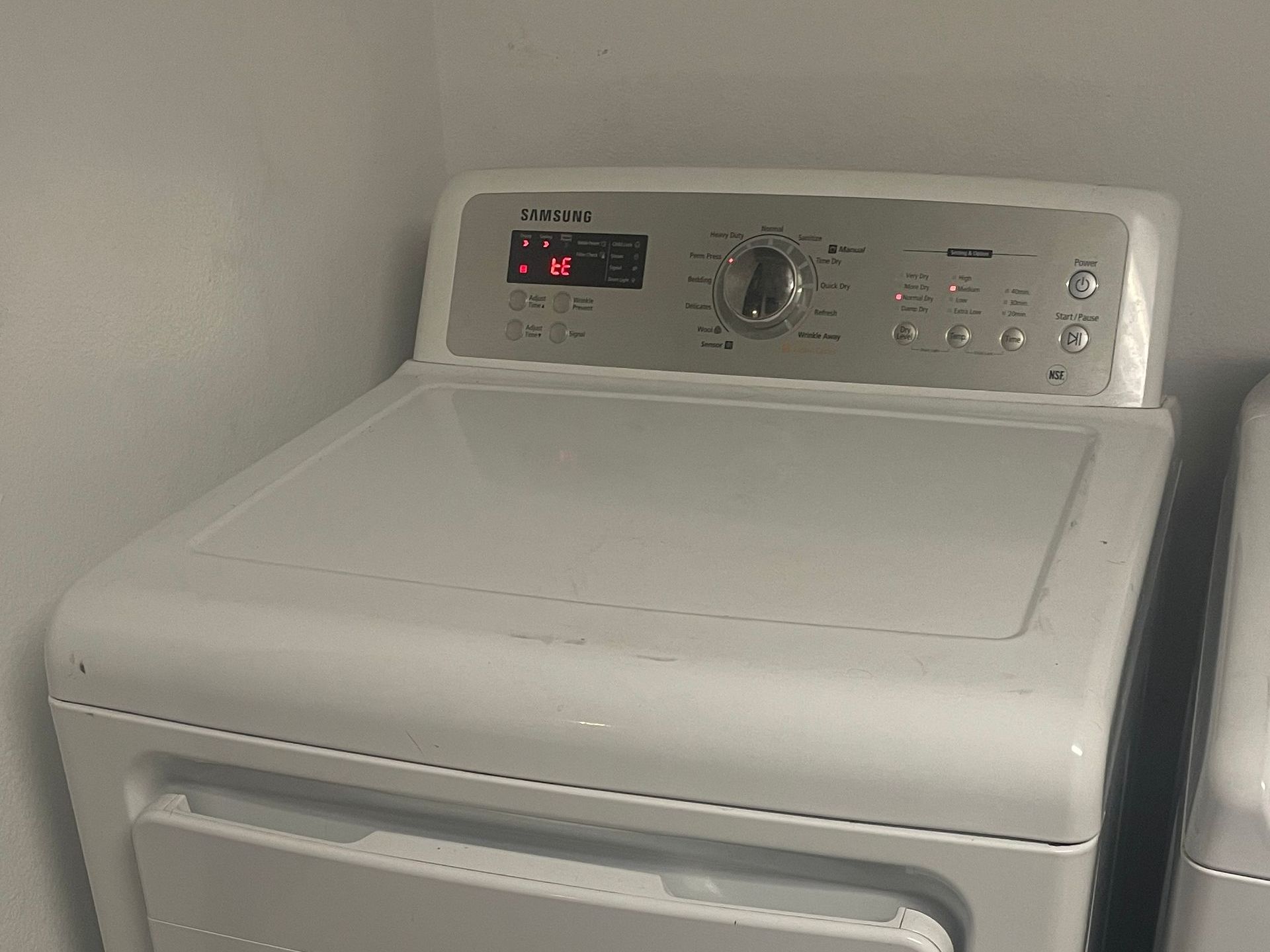 White Samsung dryer in a laundry room.