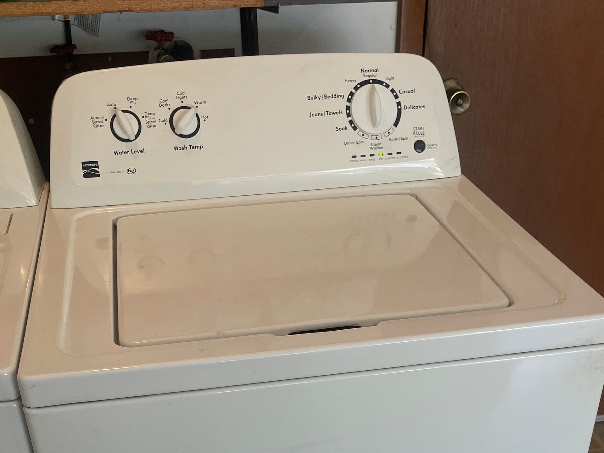 White Kenmore top-load washing machine with knobs and a central dial.