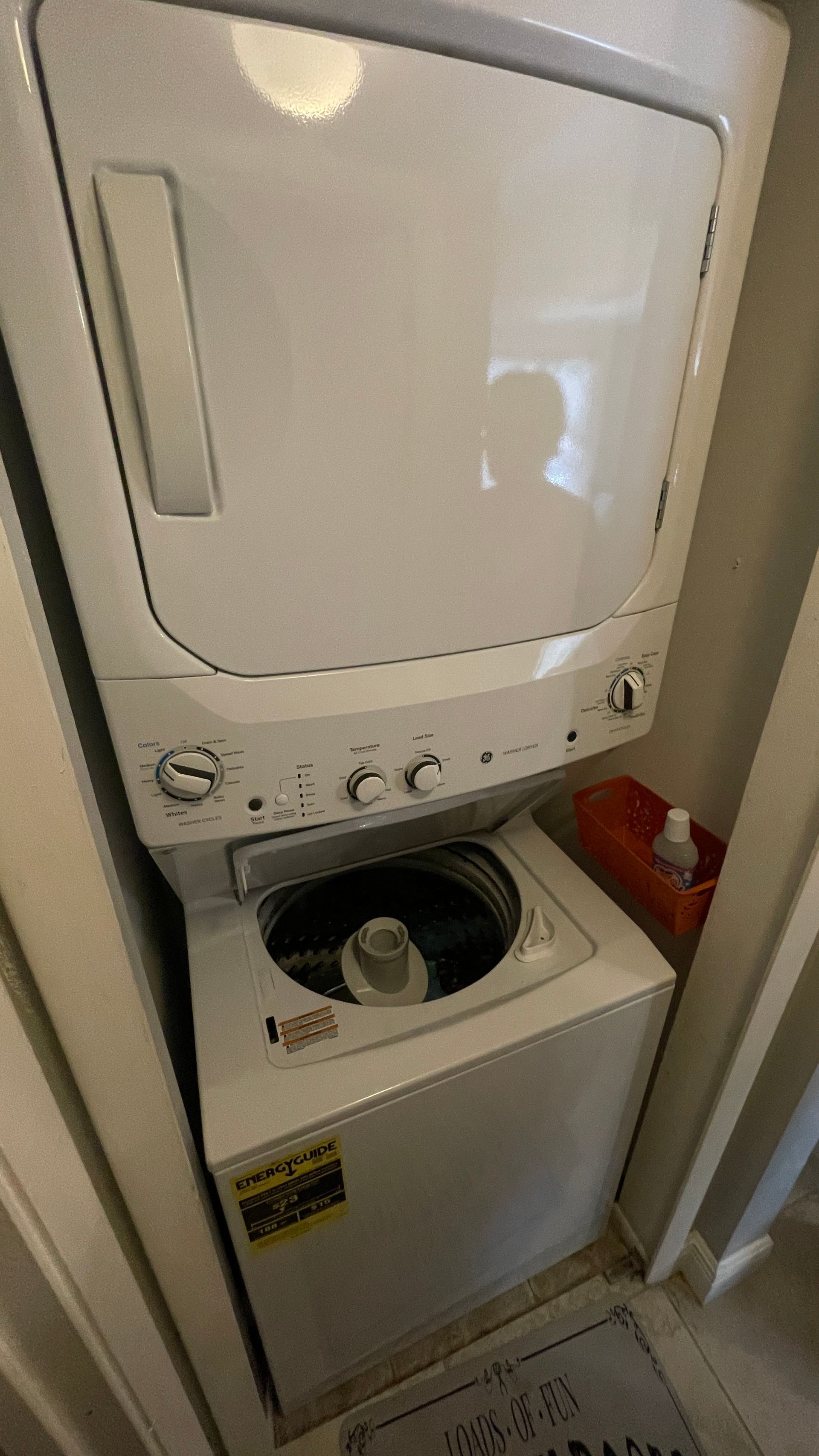 Stacked white washing machine and dryer unit in a small laundry area.