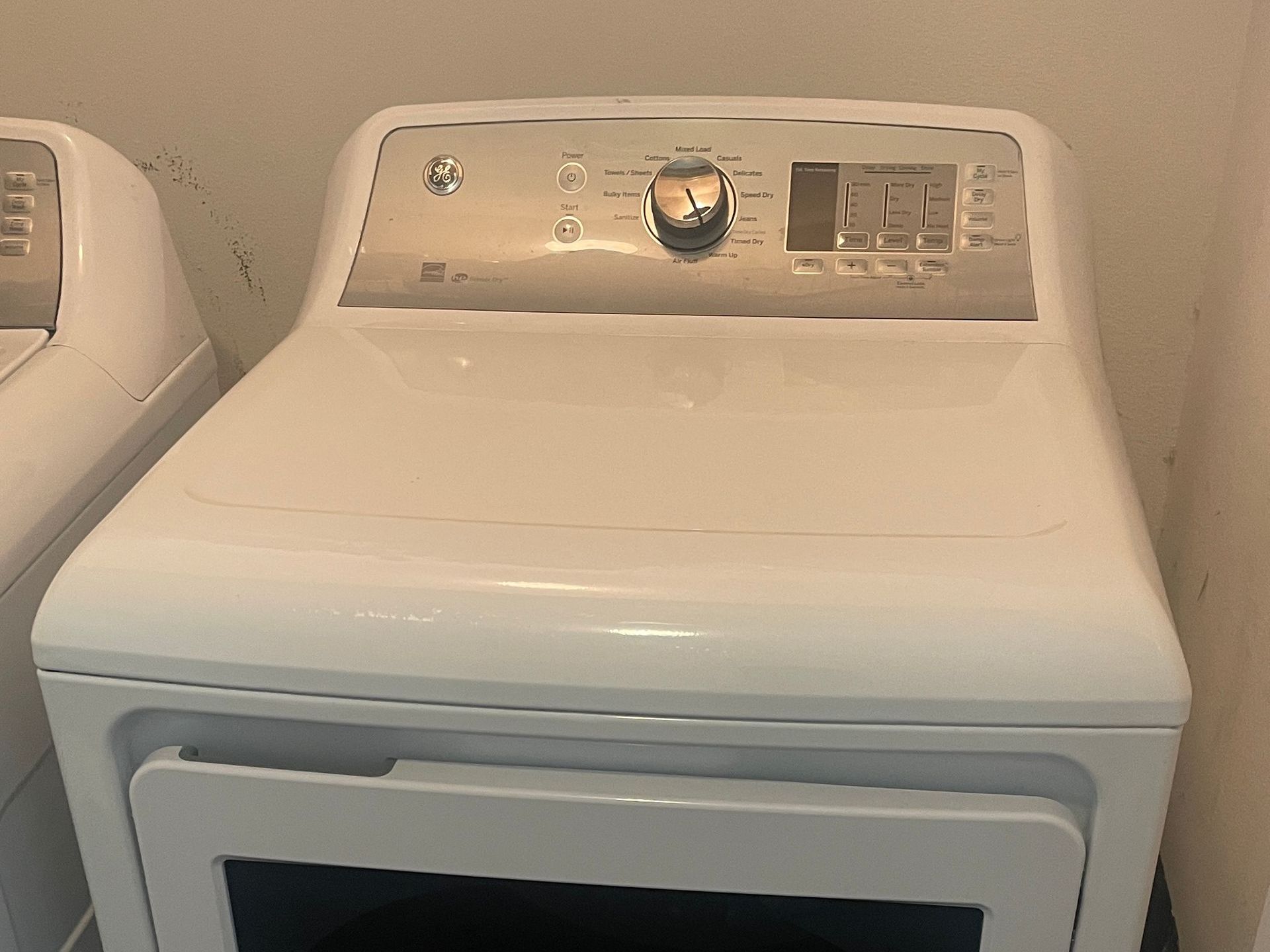 White GE dryer in a utility room. Control panel with knob and buttons.