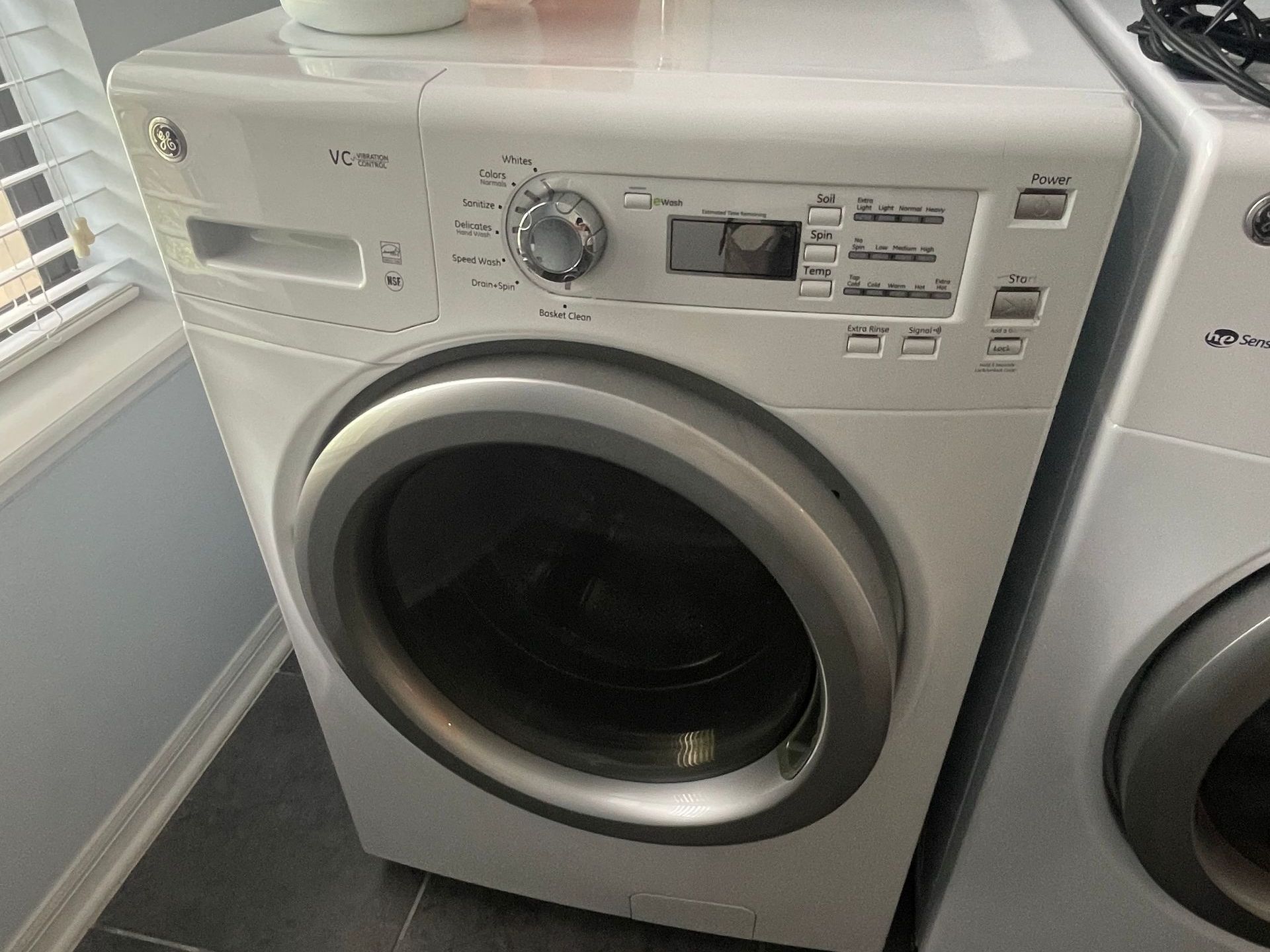 A white GE washing machine with a large round door and control panel.