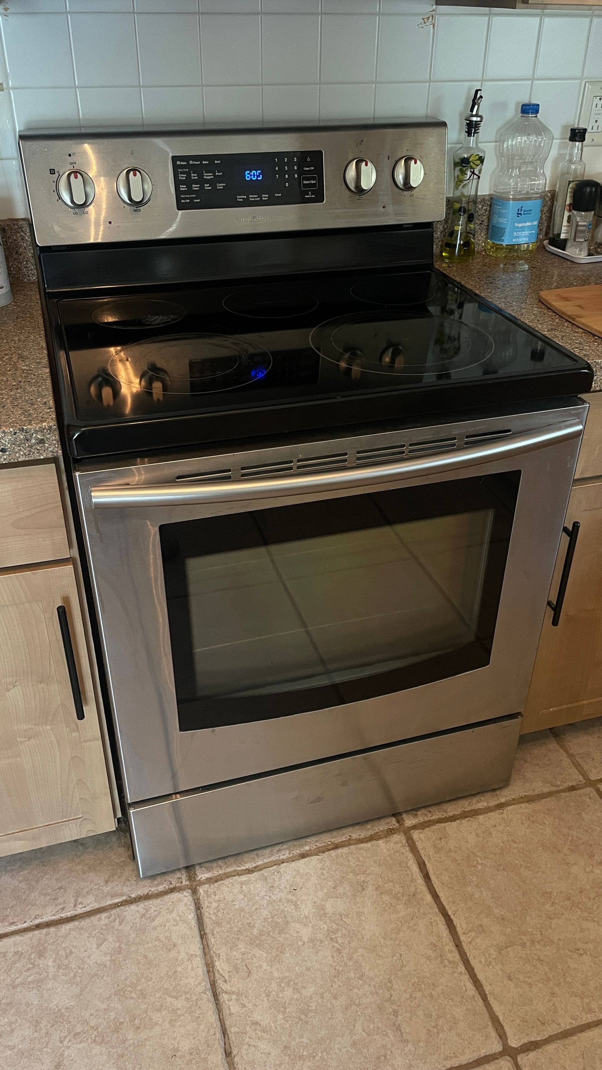 Stainless steel electric range with black cooktop, in a kitchen setting.
