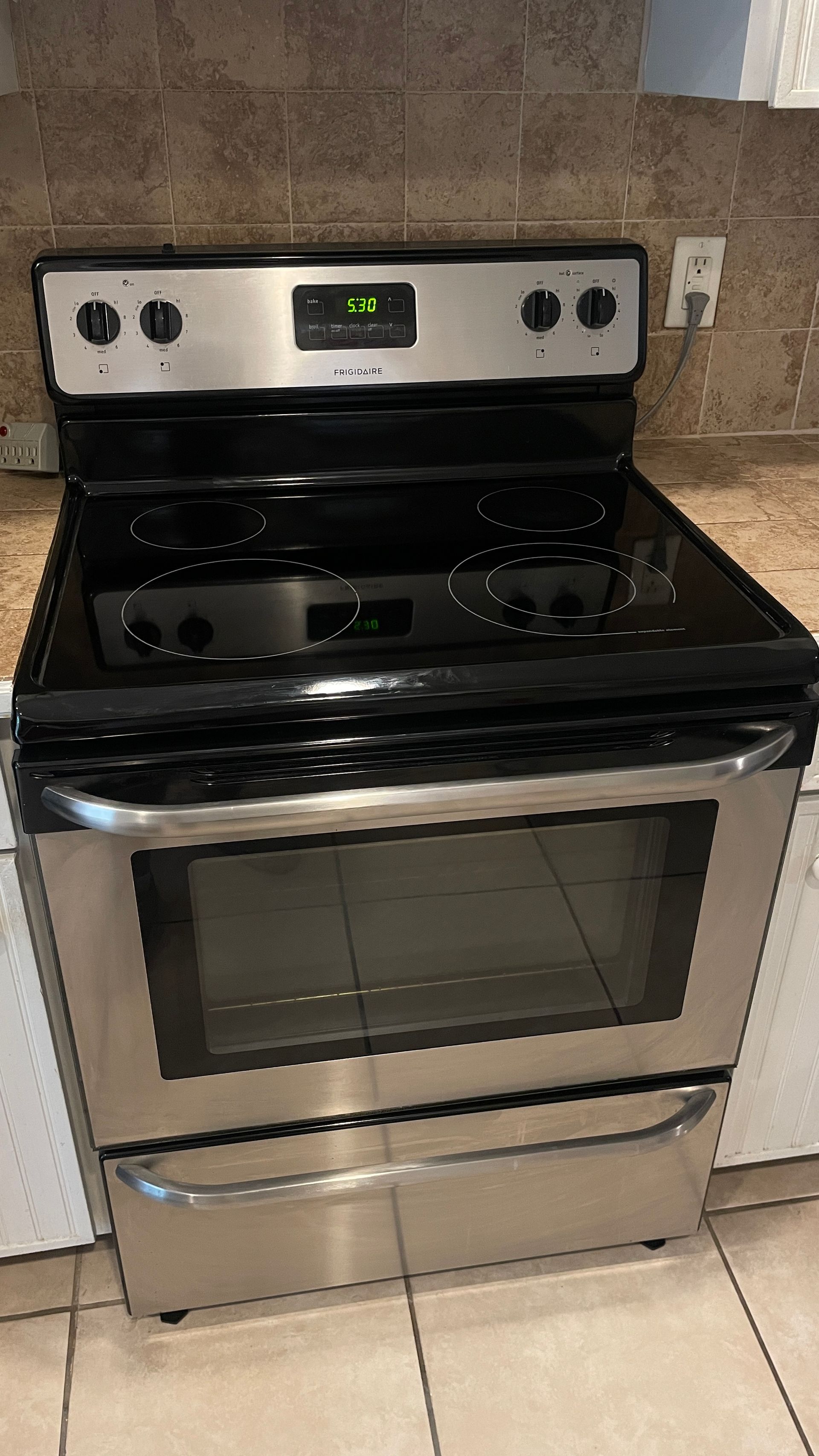Stainless steel electric range with black cooktop, oven, and storage drawer.