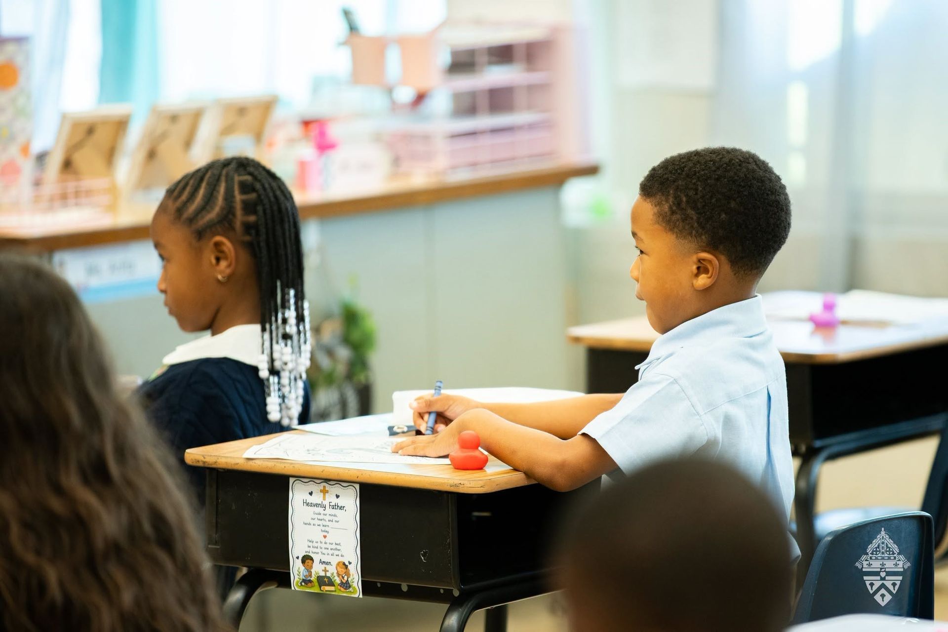 A group of children are sitting at a table holding bibs and smiling
