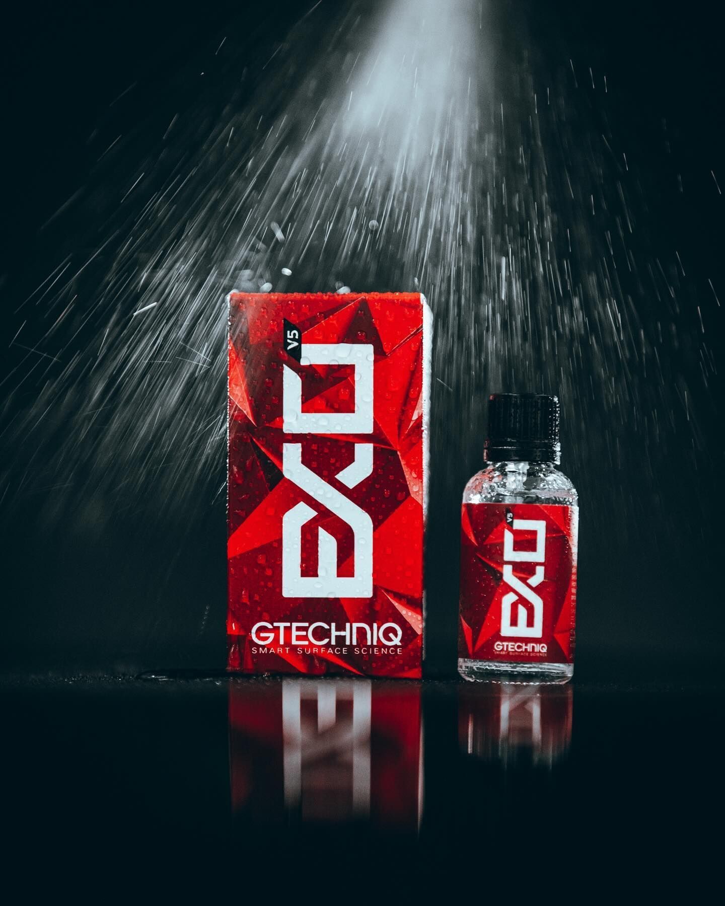 Red GTECHNIQ product box and spray bottle under dramatic spotlight on a dark background