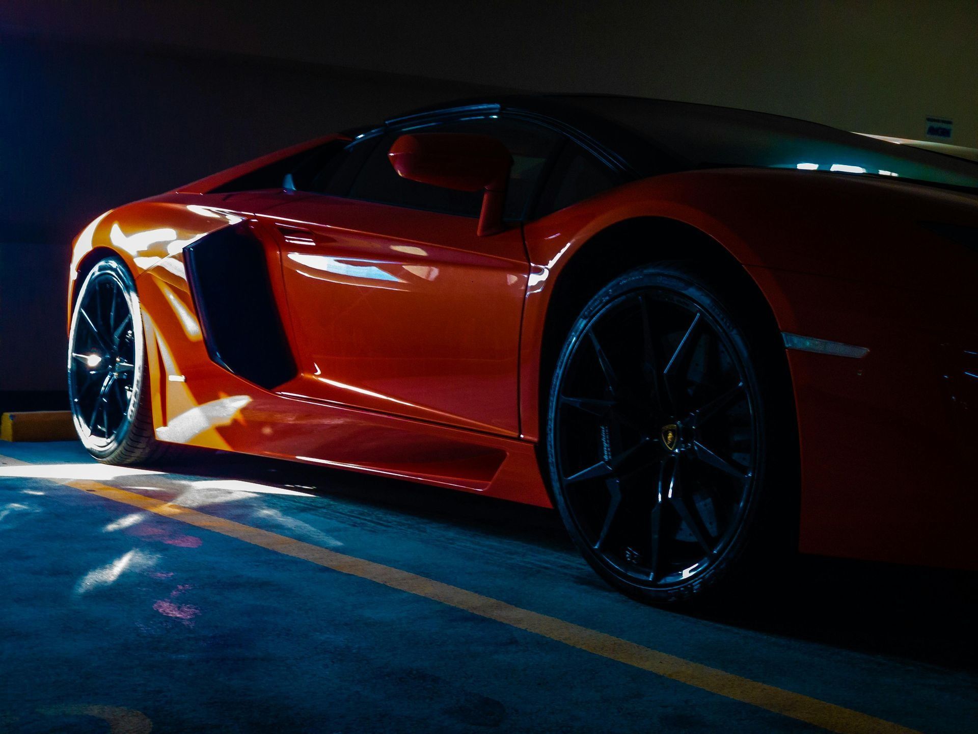 Red sports car parked at night, lit by streetlights on a dark road