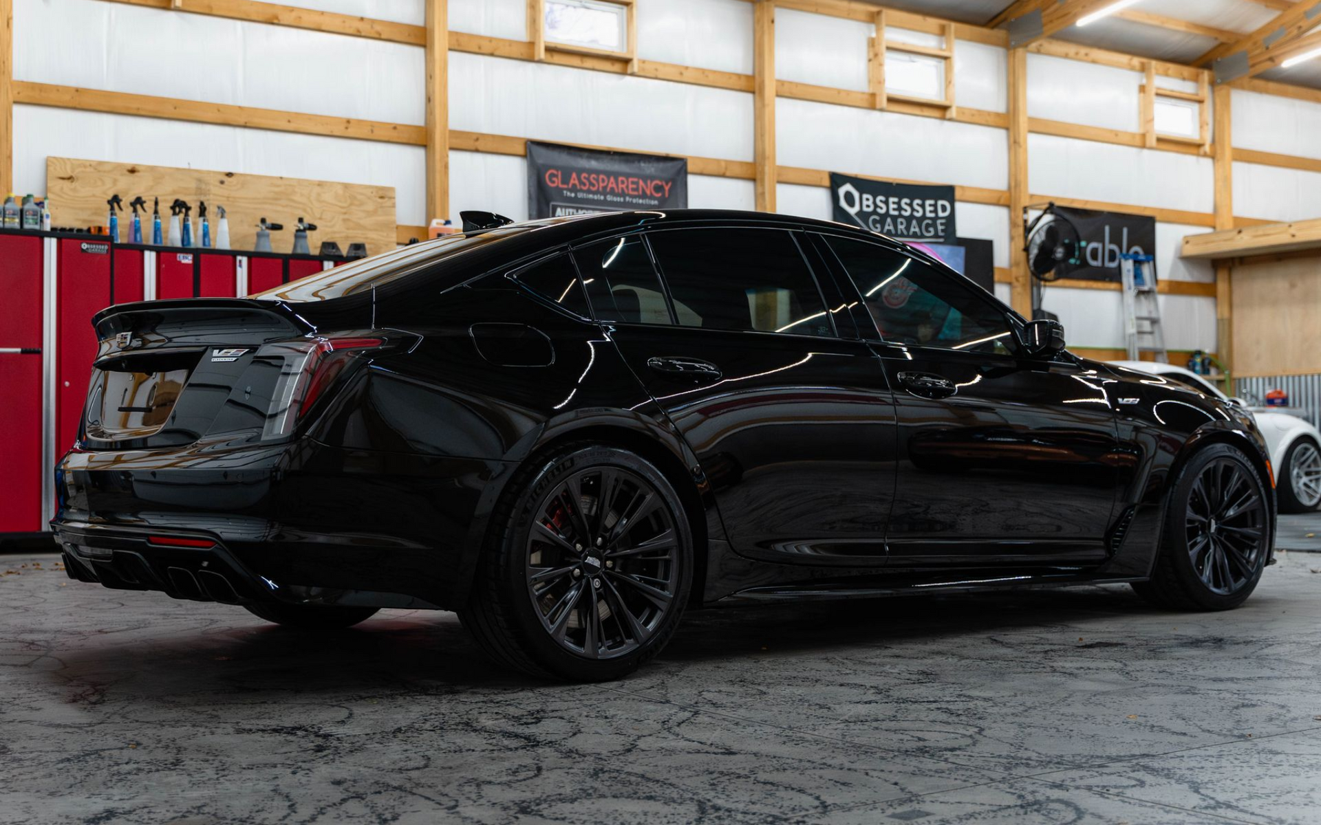 Black sedan in an auto shop garage, viewed from the side