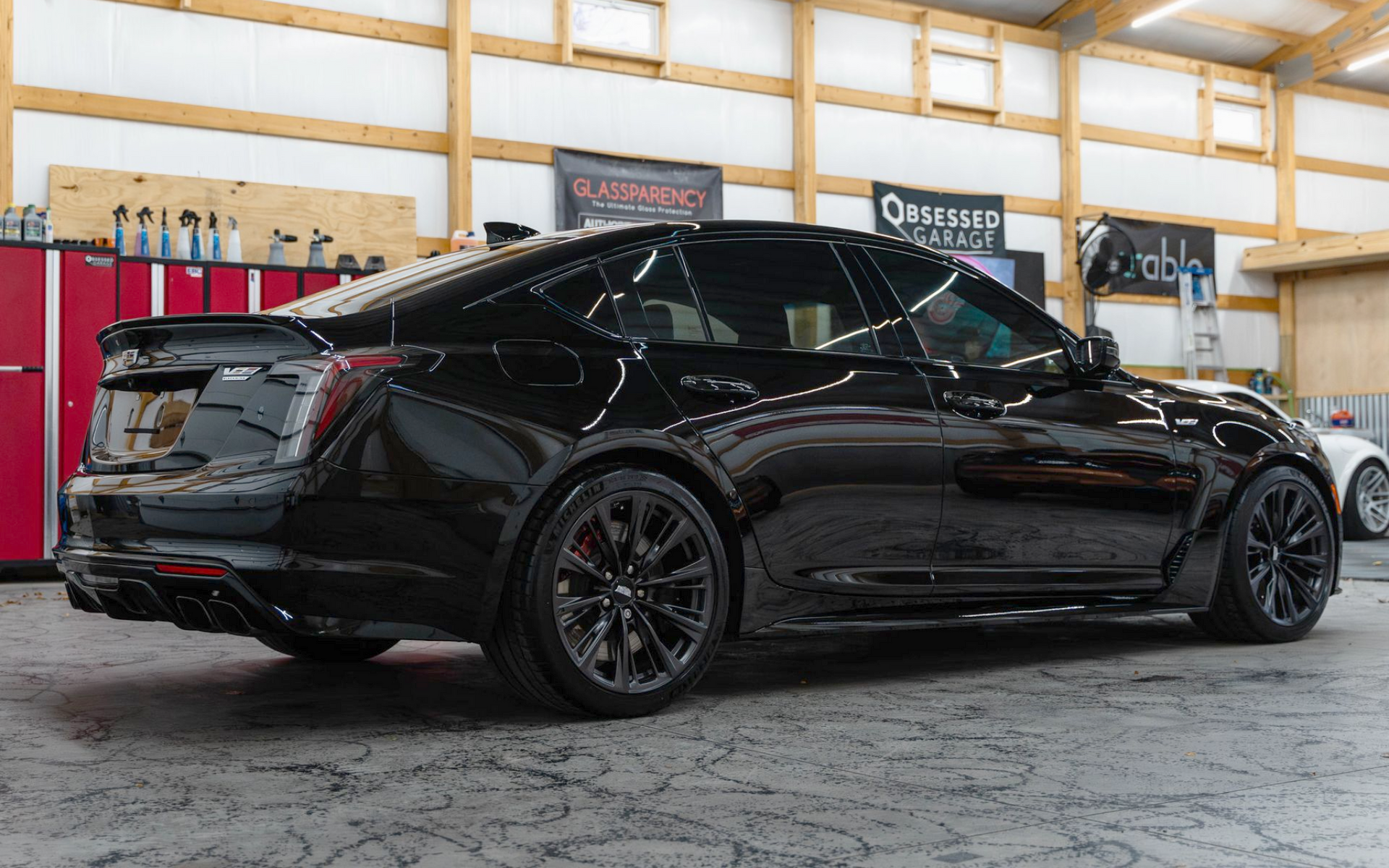 Black sedan with tinted windows parked inside a garage or auto shop.