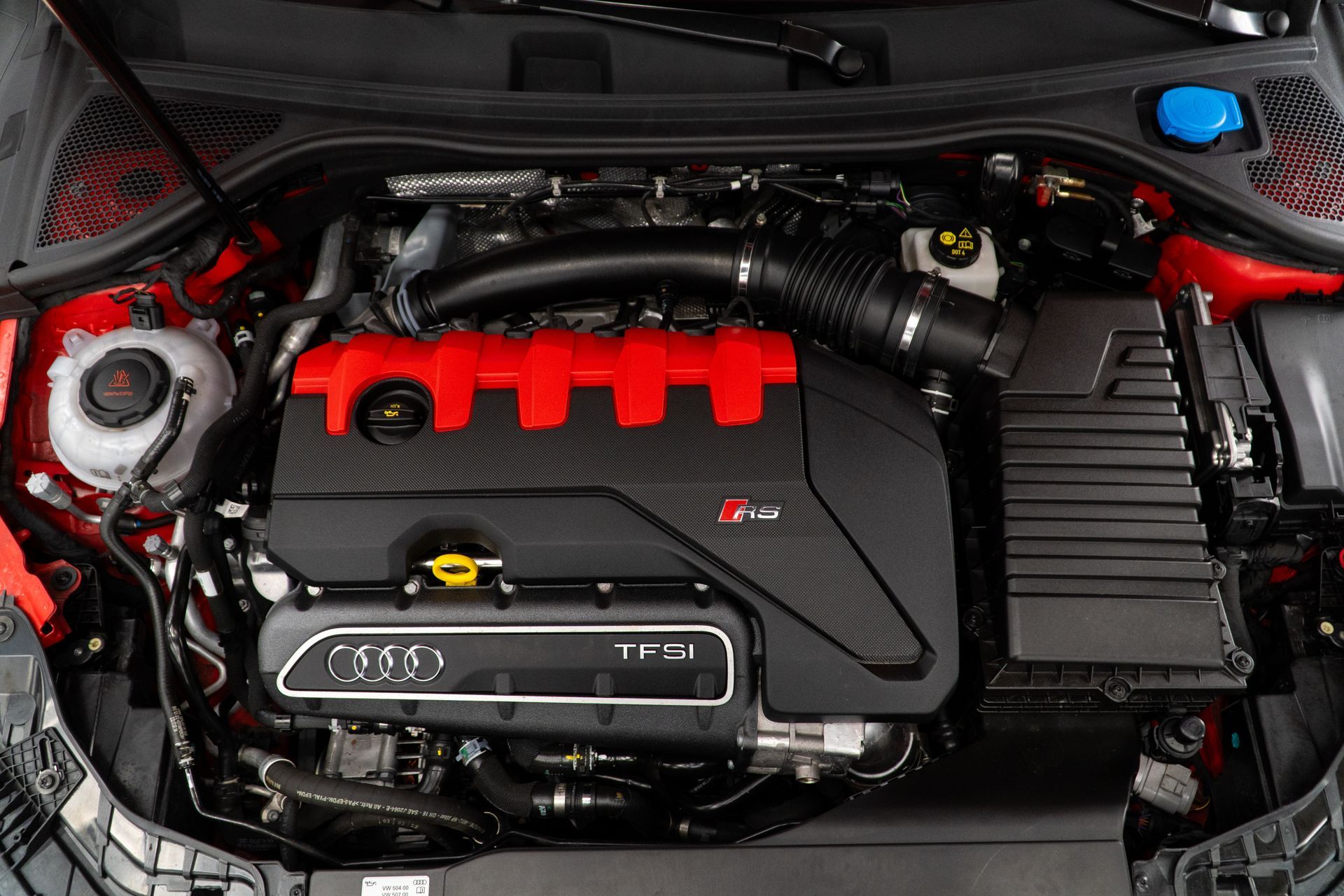 Car engine bay with red valve cover, black air intake, and visible TFSI engine cover