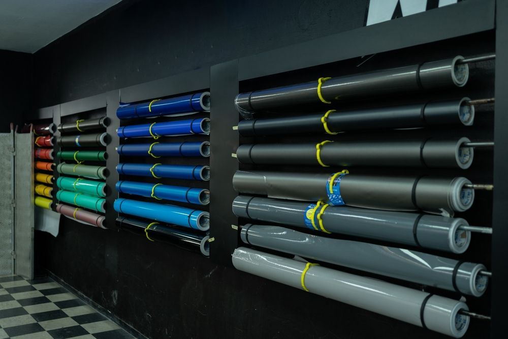 Racks of colorful and gray foam tubes stored on a black wall in a shop or workshop