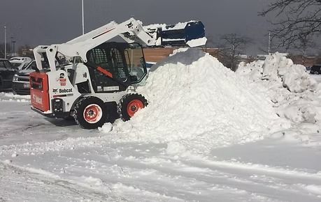 Skid-steer loader pushing a large snow pile in a snowy lot