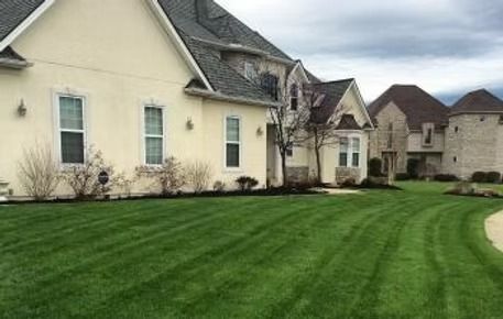 Suburban homes with manicured green lawns and a cloudy sky