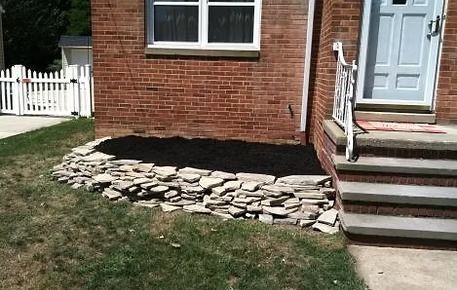 Brick house exterior with stone landscaping bed and front steps by the entryway