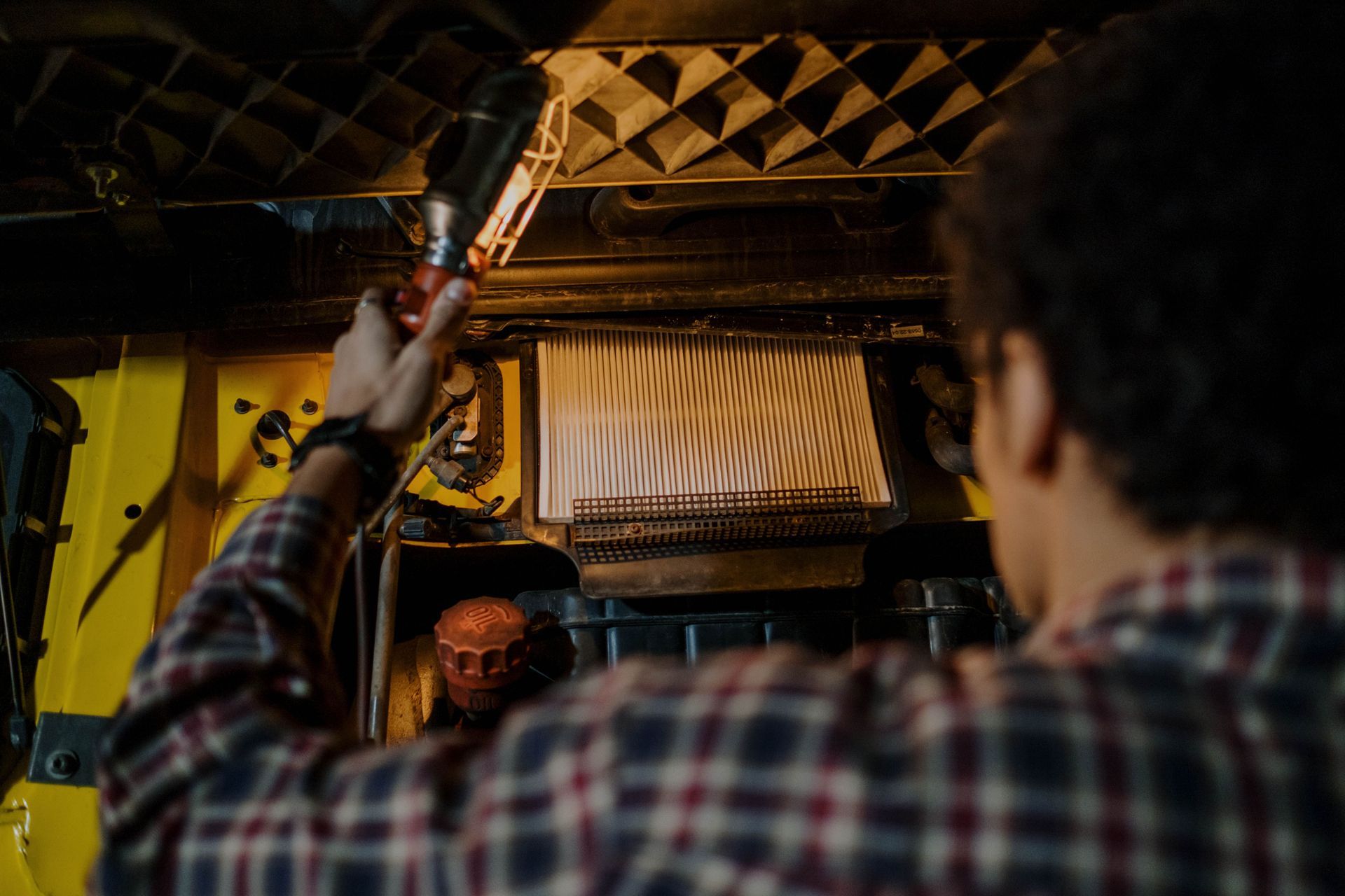 Person holding a microphone in a dim yellow room with patterned ceiling and window shades