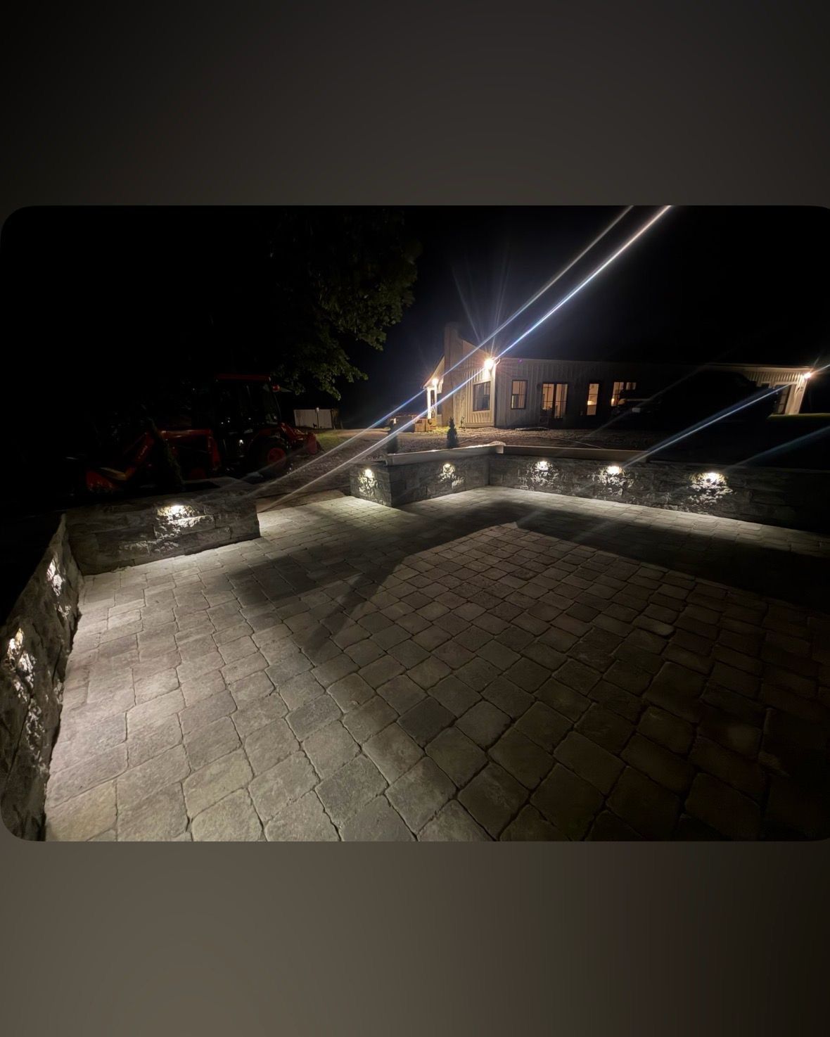 Nighttime patio with stone pavers, low lights, and a lit house in the background