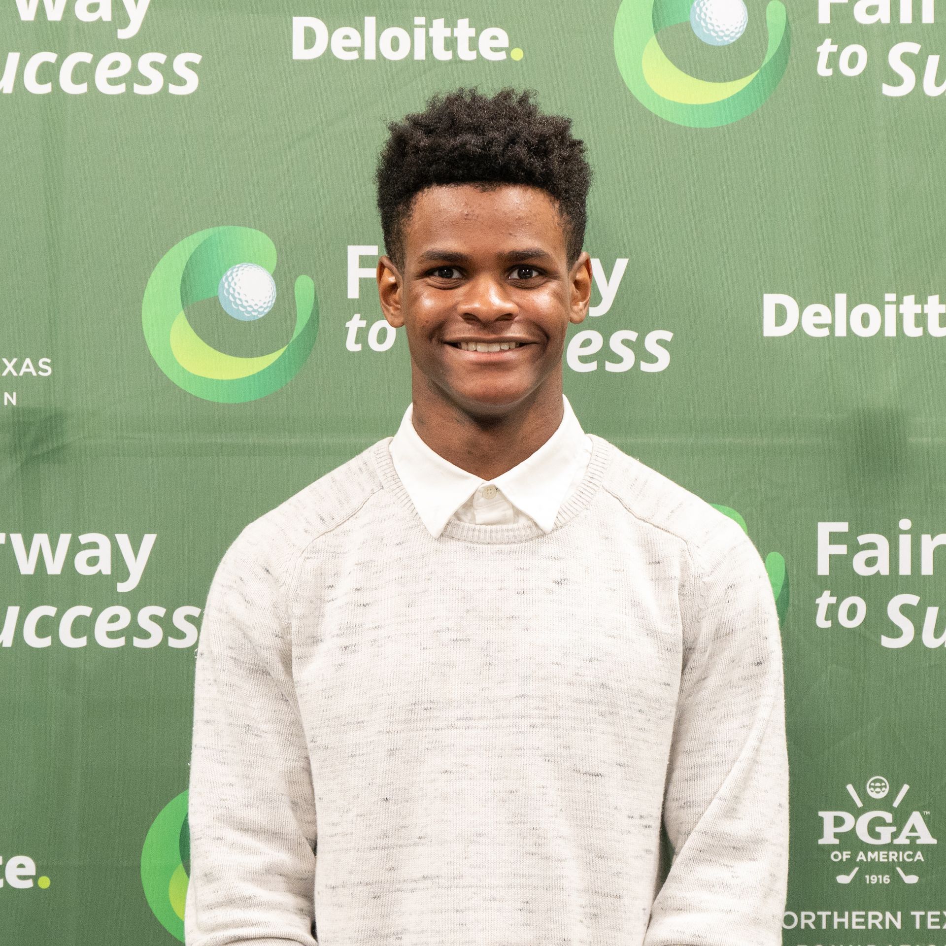 Smiling person in a white shirt standing before a green Deloitte/Fairway to Success backdrop