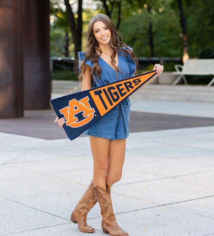 Woman in denim dress and boots holding a blue-and-orange