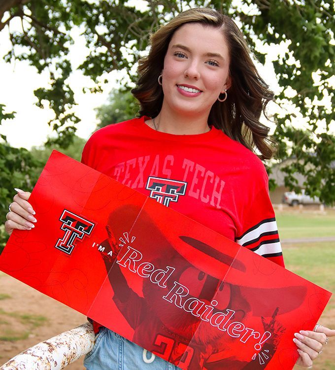 Woman in red Texas Tech shirt holding a red Texas Tech sign outdoors