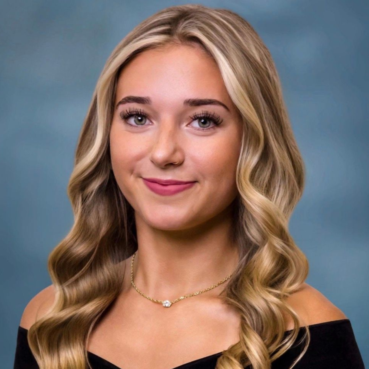 Portrait of a smiling woman with blonde wavy hair against a blue background