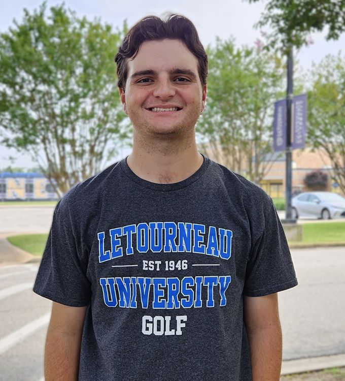 Person smiling outdoors in a dark “LeTourneau University Golf” T-shirt