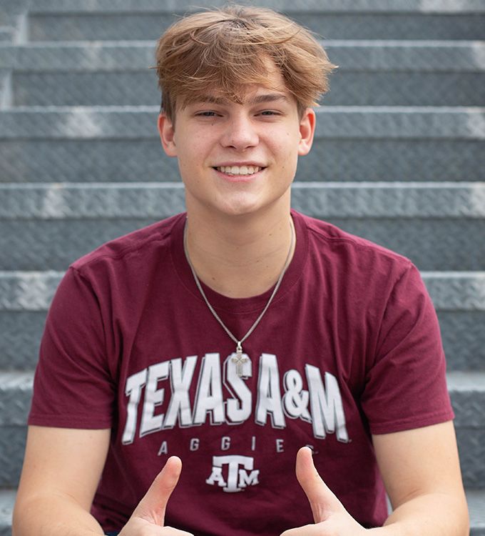 Smiling person in a maroon Texas A&M shirt sitting on outdoor steps