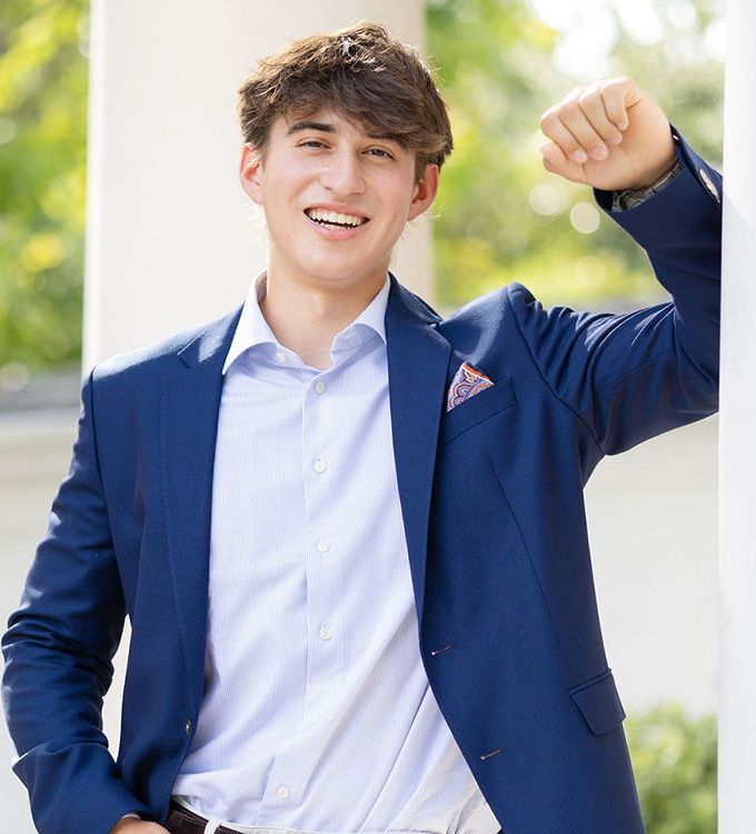 Smiling man in a blue suit with raised fist outdoors in bright sunlight