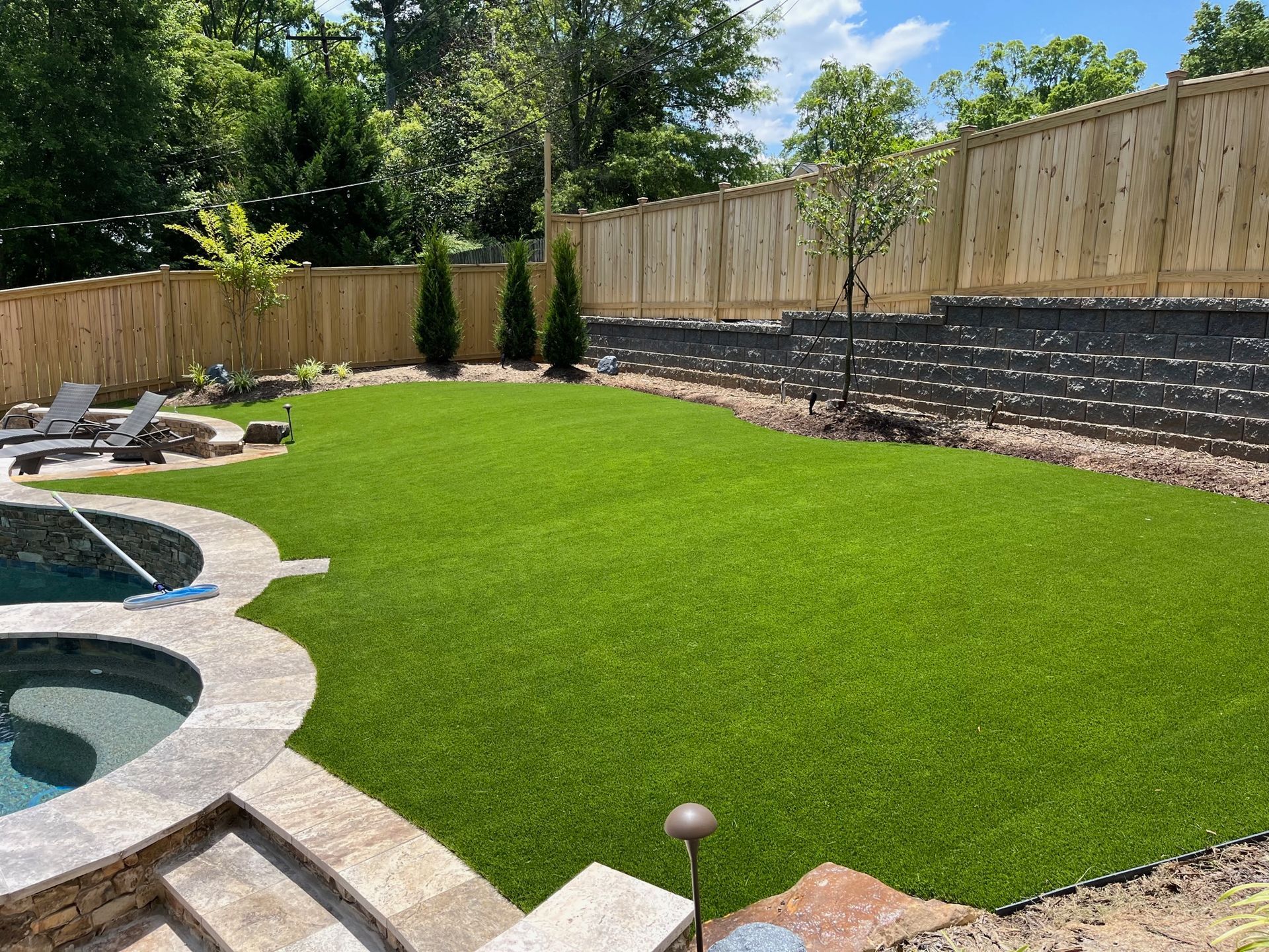 A backyard with a swimming pool and a large lawn.