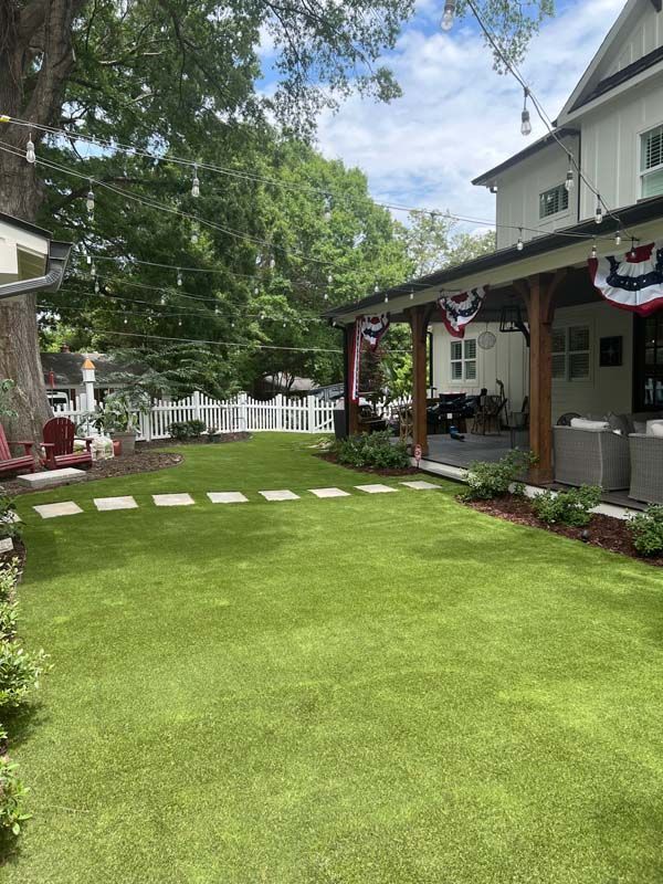 There is a large lawn in front of a house with a porch.