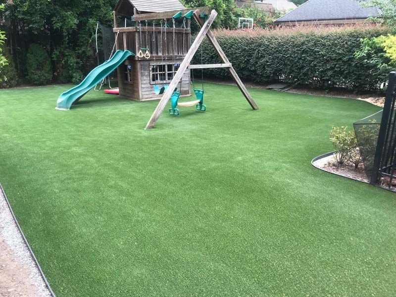 A playground with a slide and swings in a backyard.