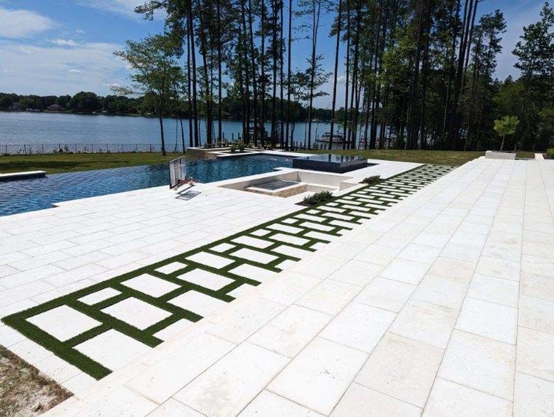 A patio with a swimming pool and trees in the background