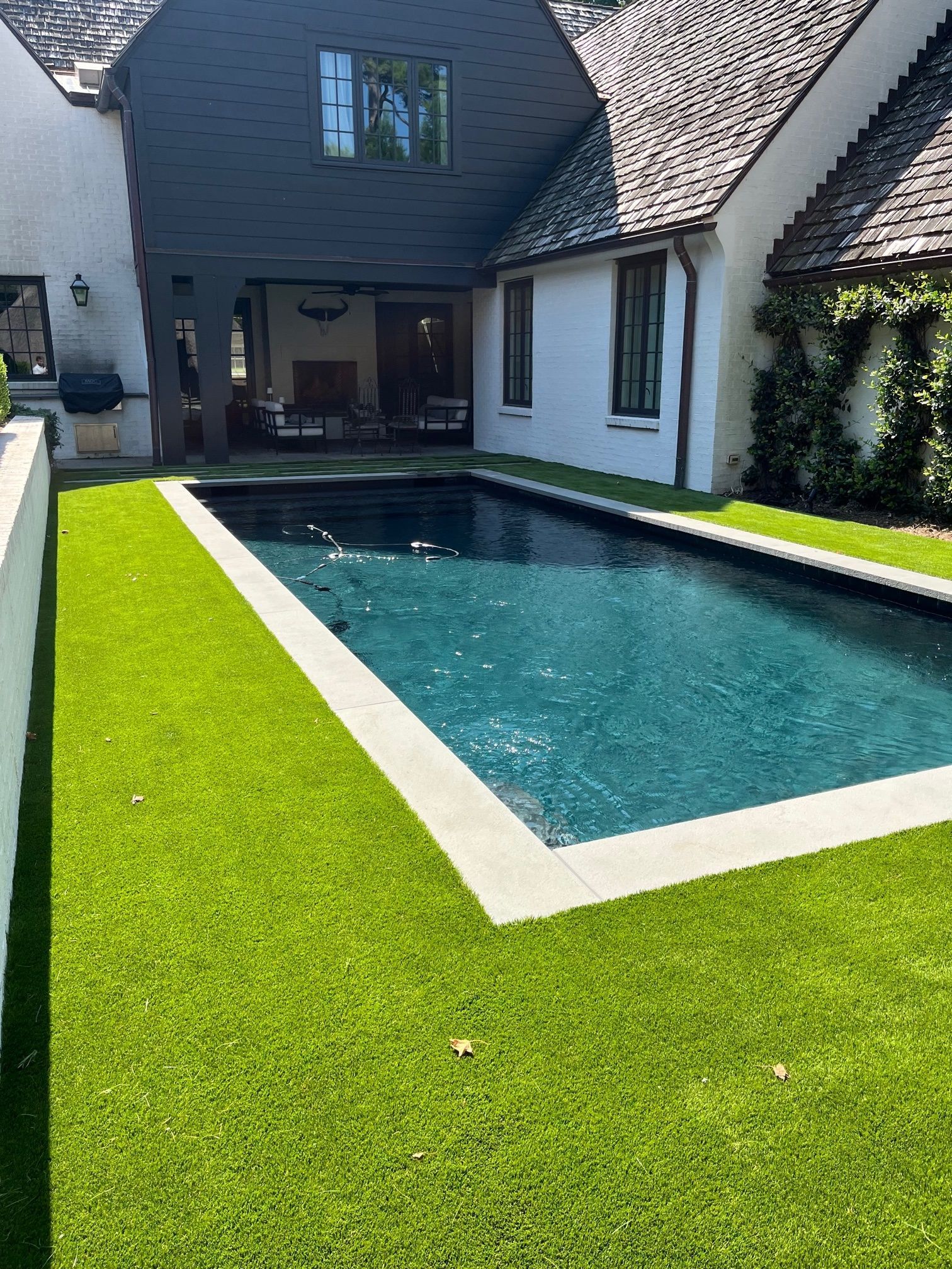 There is a large swimming pool in the backyard of a house.