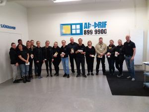 Hópur fólks situr fyrir í björtu anddyri skrifstofu með AF-PRIF skilti á veggnum.