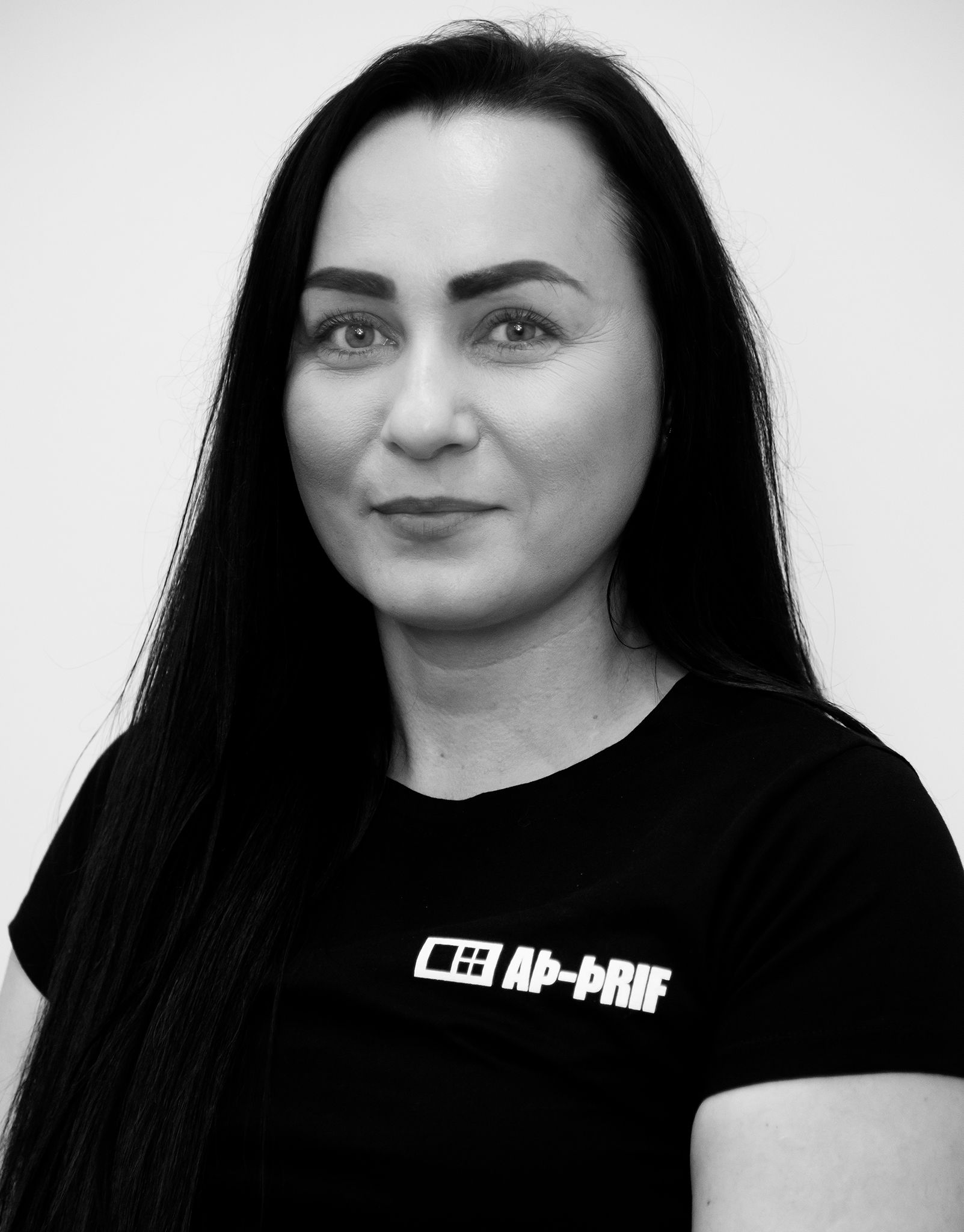 Svart-hvítt portrett af manneskju með sítt dökkt hár í svörtum bol á sléttum bakgrunni