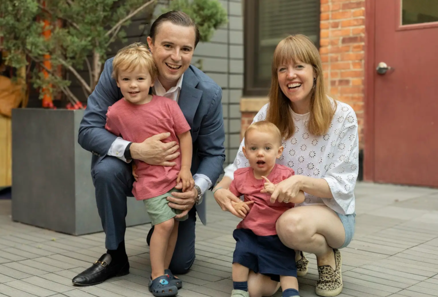 A family is posing for a picture in front of a building.