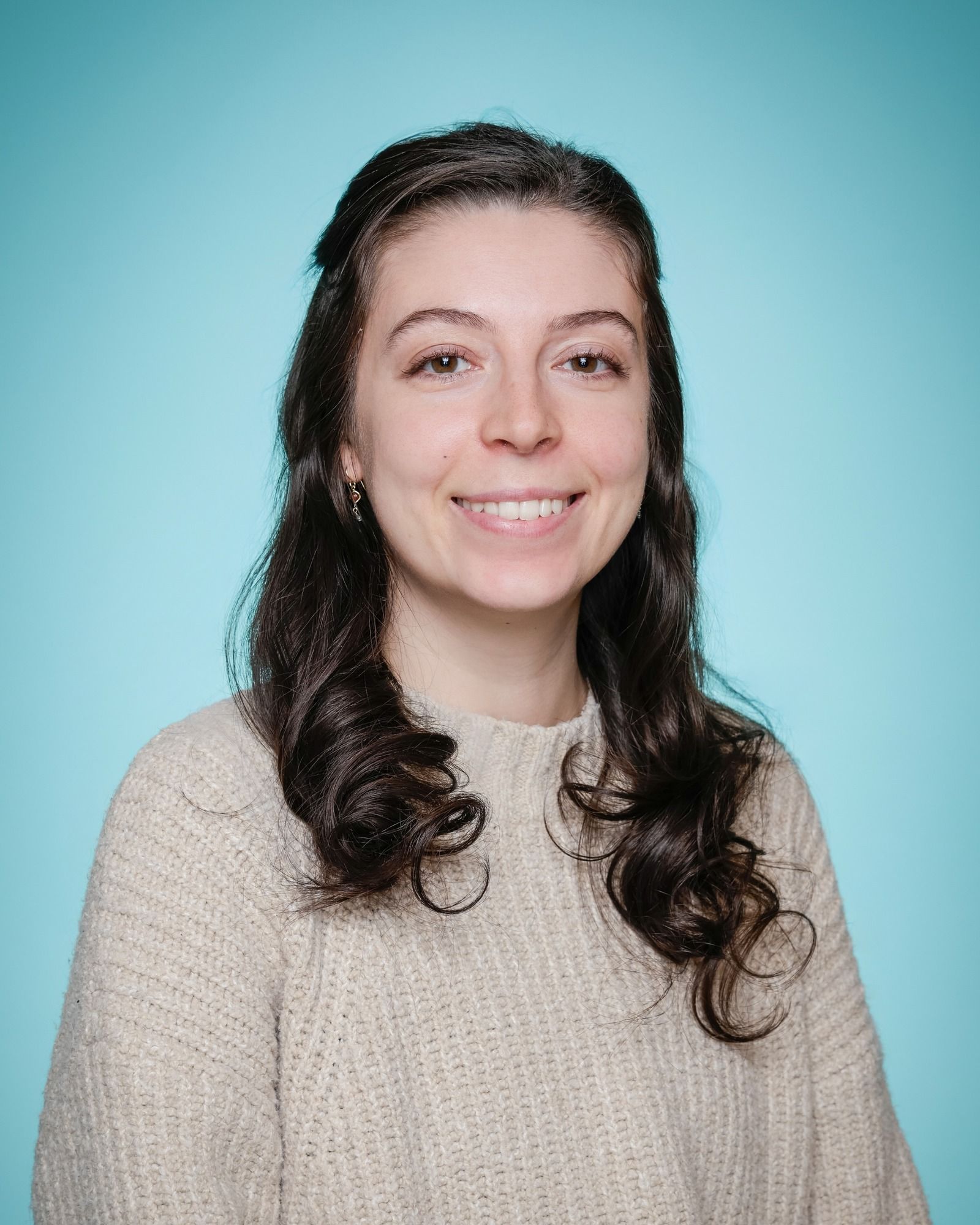 A woman in a white shirt is smiling in front of a bookshelf.