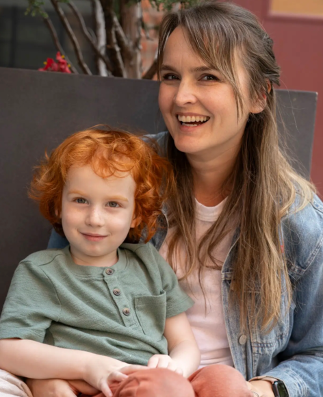 A woman is holding a little boy with red hair.