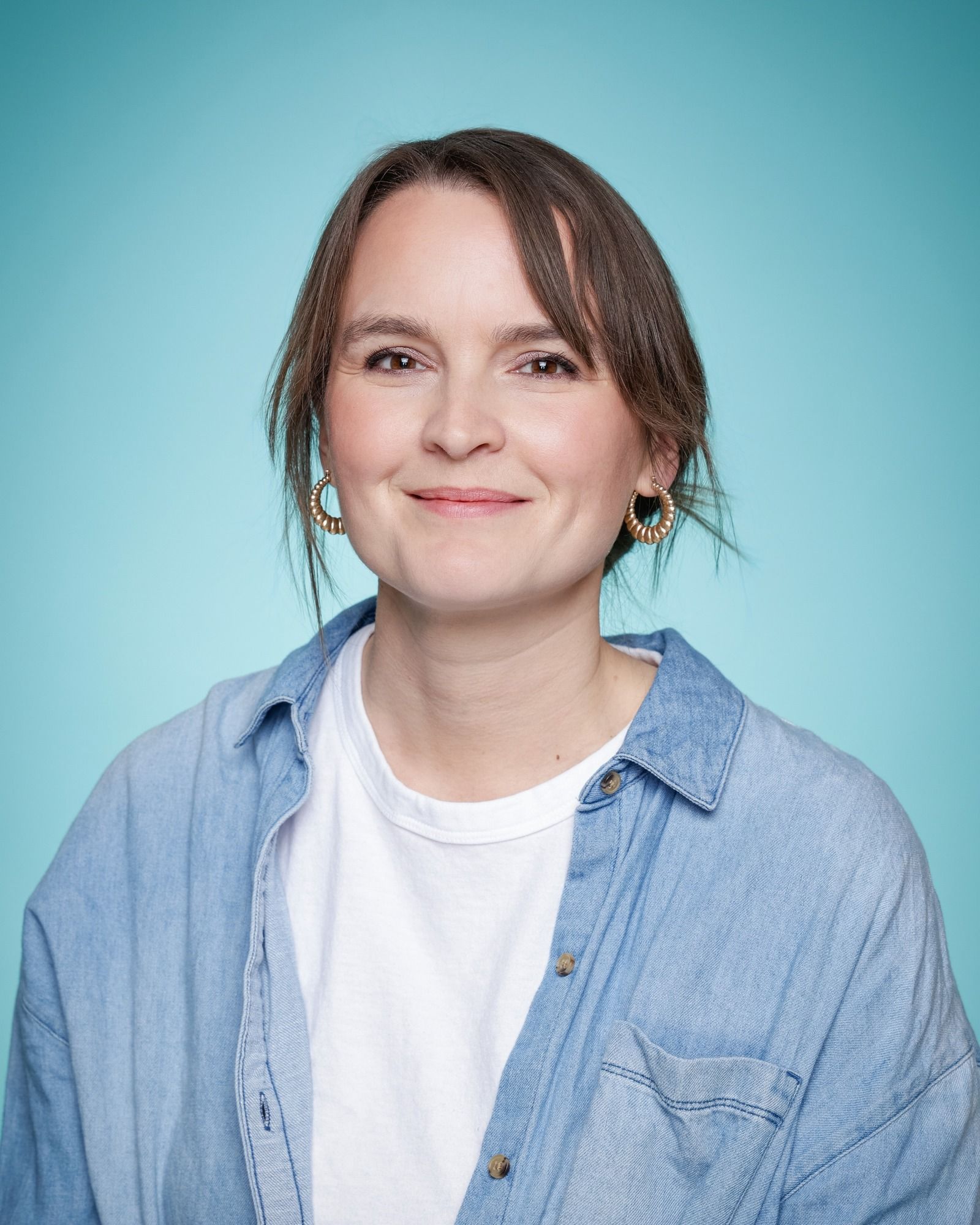A woman is smiling in front of a bookshelf full of books
