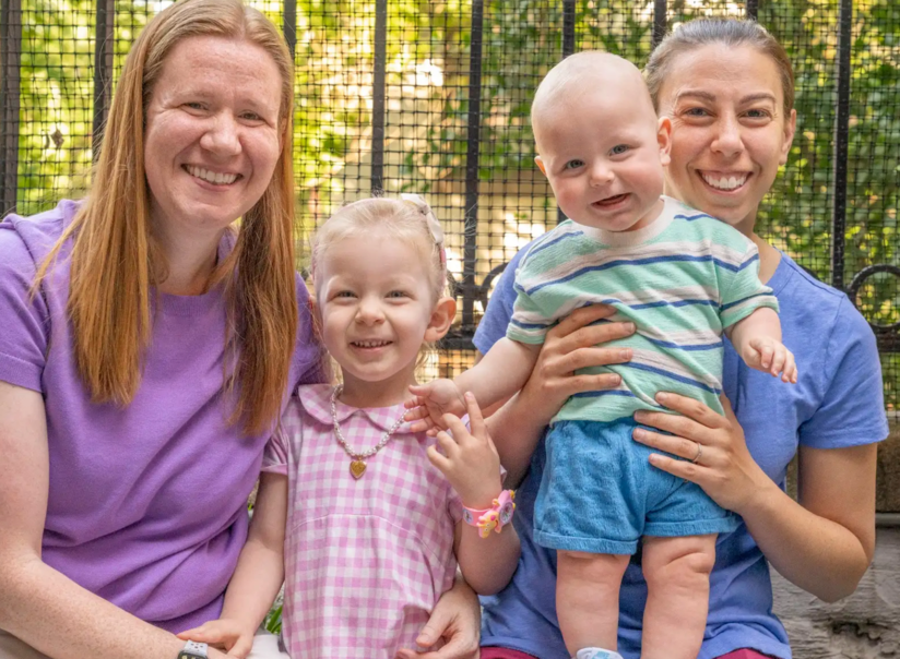 Two women are sitting next to each other holding two children.