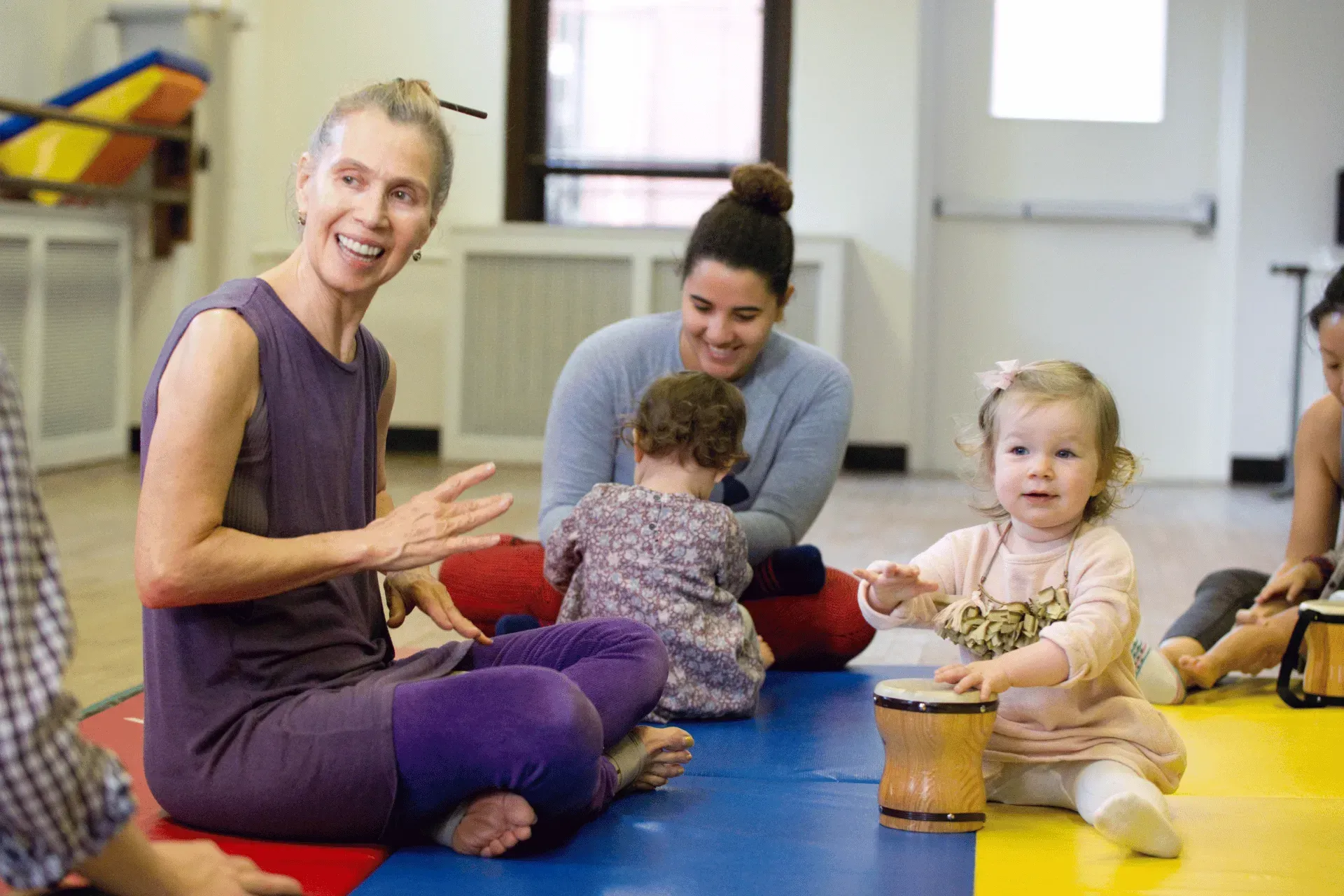 A group of people are sitting on the floor playing with babies.