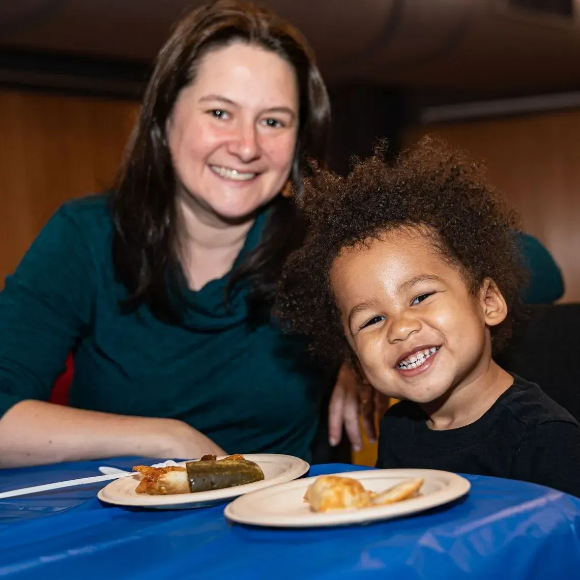 A woman and child are sitting at a table with plates of food
