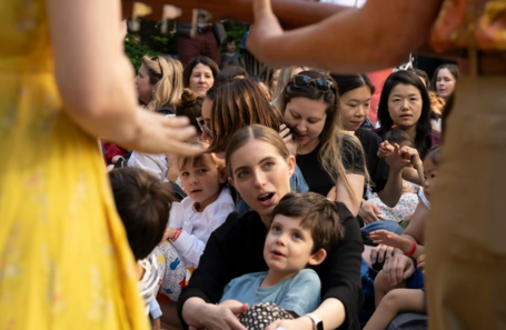 A woman is holding a child in her arms in front of a crowd of people.