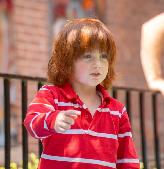 A young boy with red hair is pointing at something