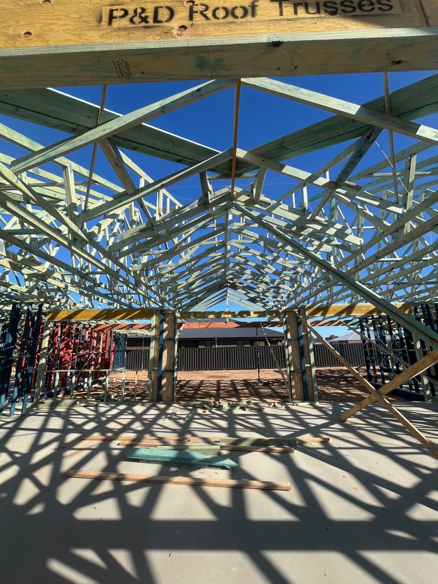 Construction of a building's roof frame under a bright blue sky. 