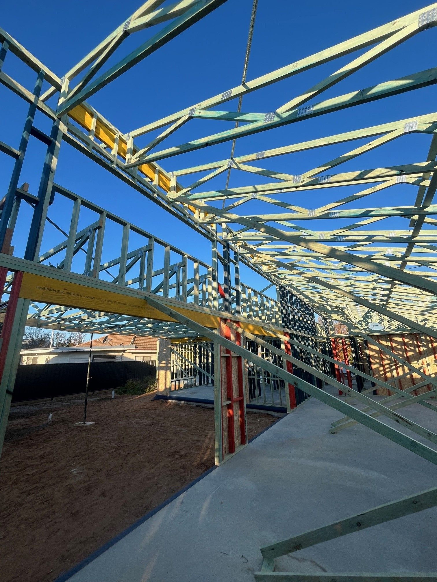 Construction of a house frame under a bright blue sky.