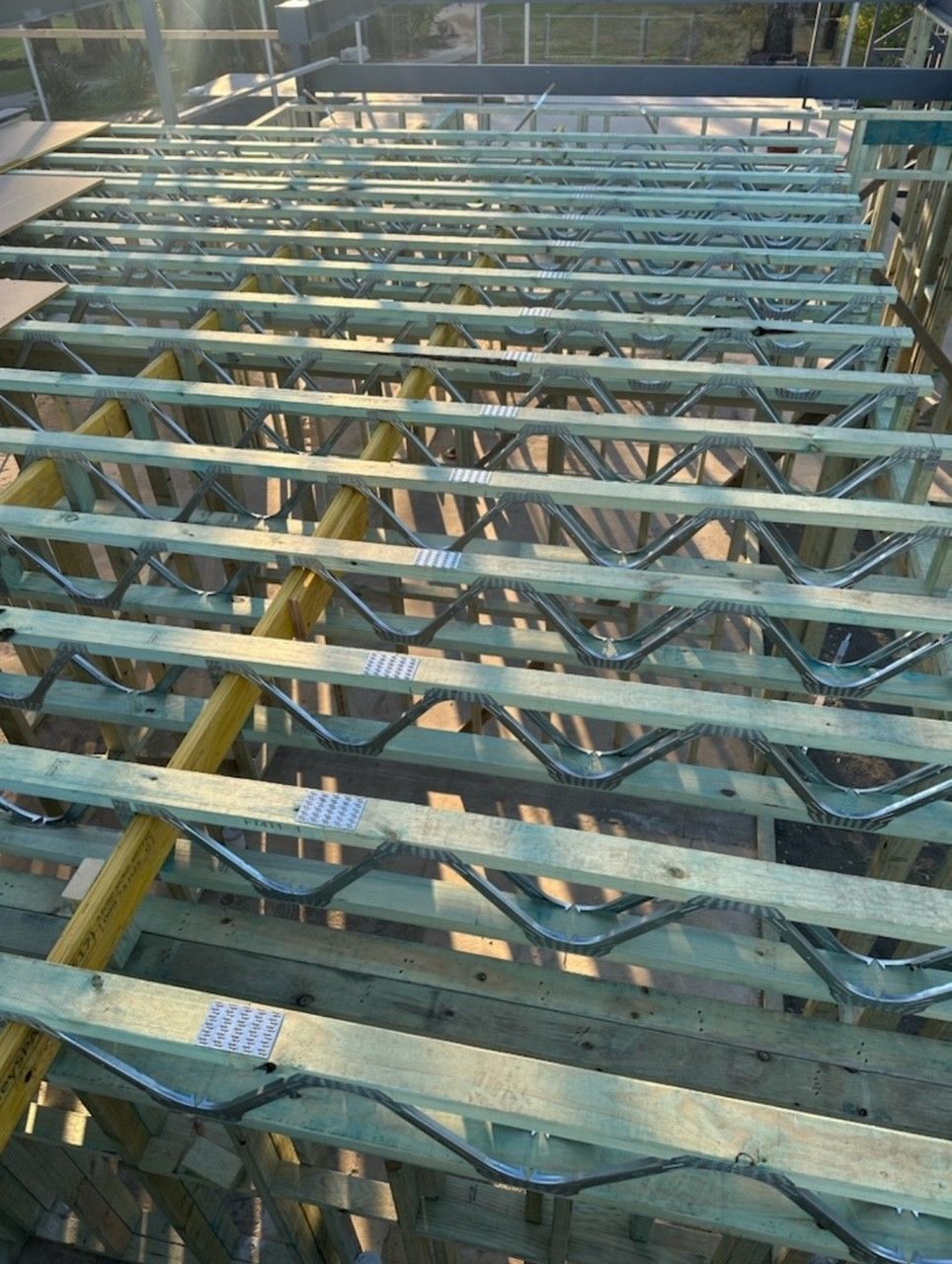 The roof of a building is being built with wooden beams and metal beams.